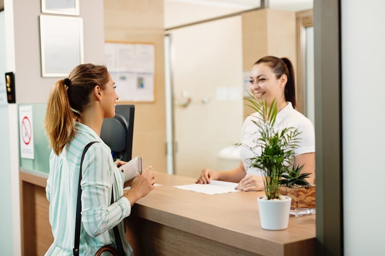 photo of brunette reception staff smiling with blonde female patient